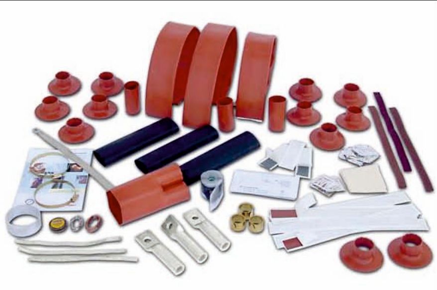 Contents of a 36 kV outdoor termination kit laid out: large red rain sheds, red and black tubes, a breakout, lugs, clips, tapes and instructions