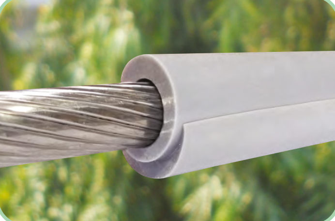 Grey silicone overhead line cover fitted over a bare stranded aluminium conductor, split seam visible along its length