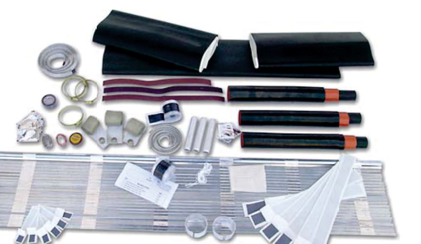A medium-voltage straight-through joint kit laid out: black outer sleeves, insulating tubes with red stress-control ends, copper mesh, jubilee clips, tapes, connectors and a metal wrap-around case
