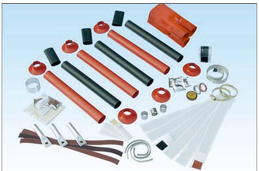 Contents of a GALA 11 kV outdoor termination kit laid out: red and black heat shrink tubes, a red three-finger breakout, red rain sheds, cable lugs, earthing braid, clips, mastic strips and cleaning tissues